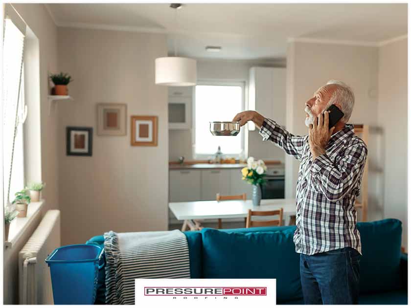 3641-1626688115-man-on-phone-holding-up-metal-bowl-to-catch-ceiling-leak.jpg