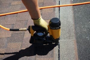 Nailing roofing shingles onto a roof.